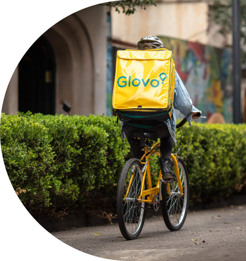 A Glovo delivery rider cycling around a city