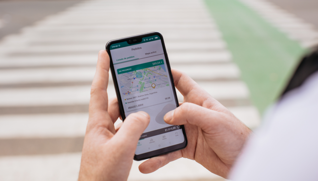 Someone holding a mobile phone using the location functionality of the Glovo Rider app
