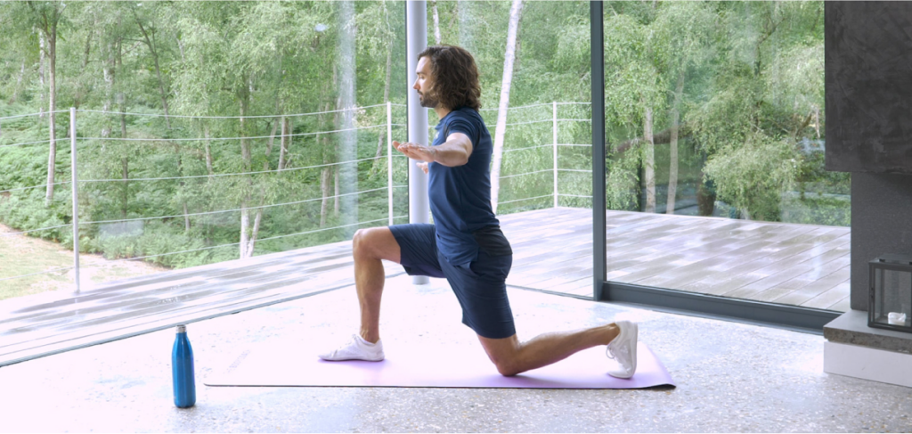 Joe Wicks stretching on a pink gym mat